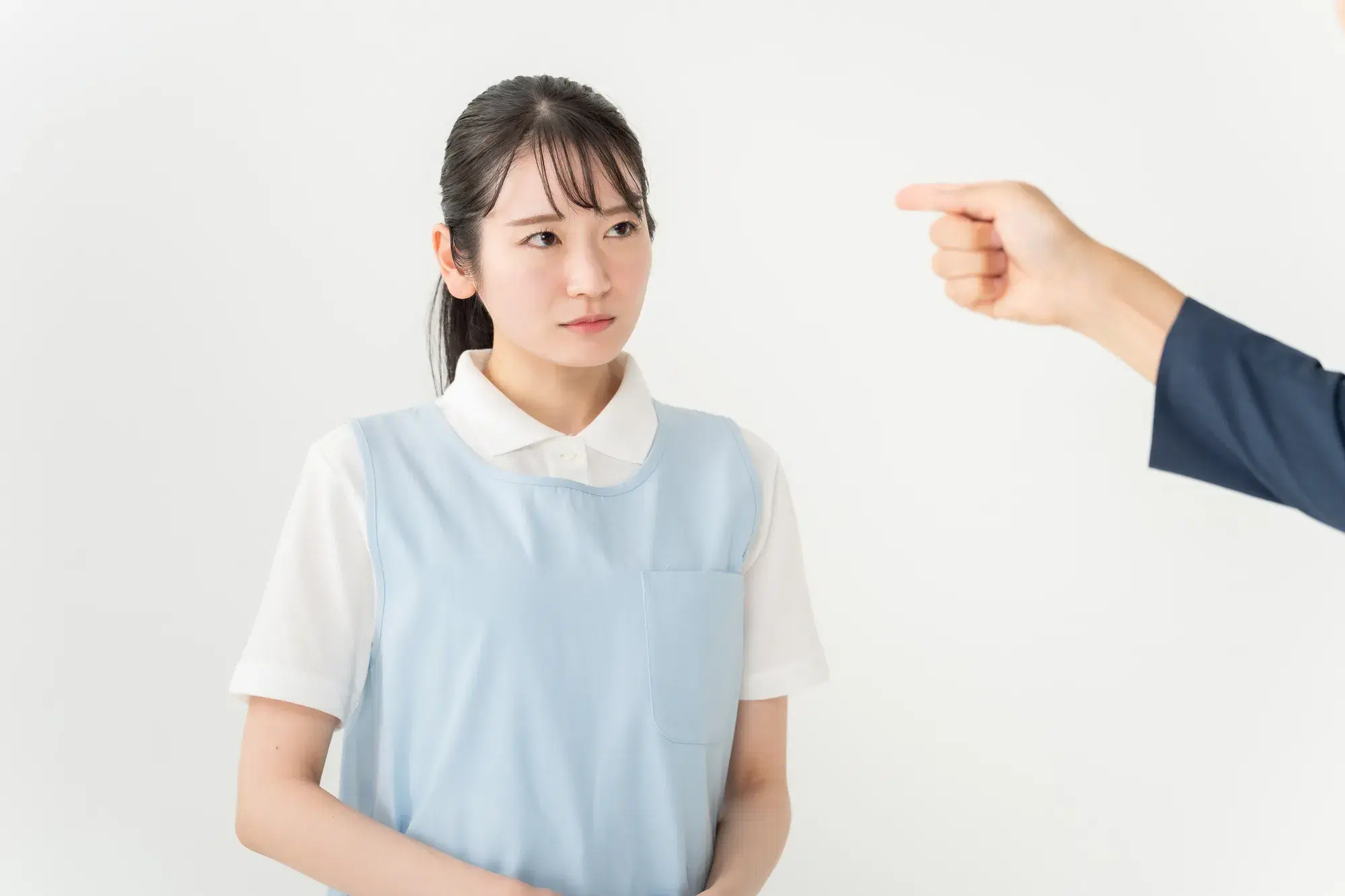 指を指されている水色のエプロンを着用した女性