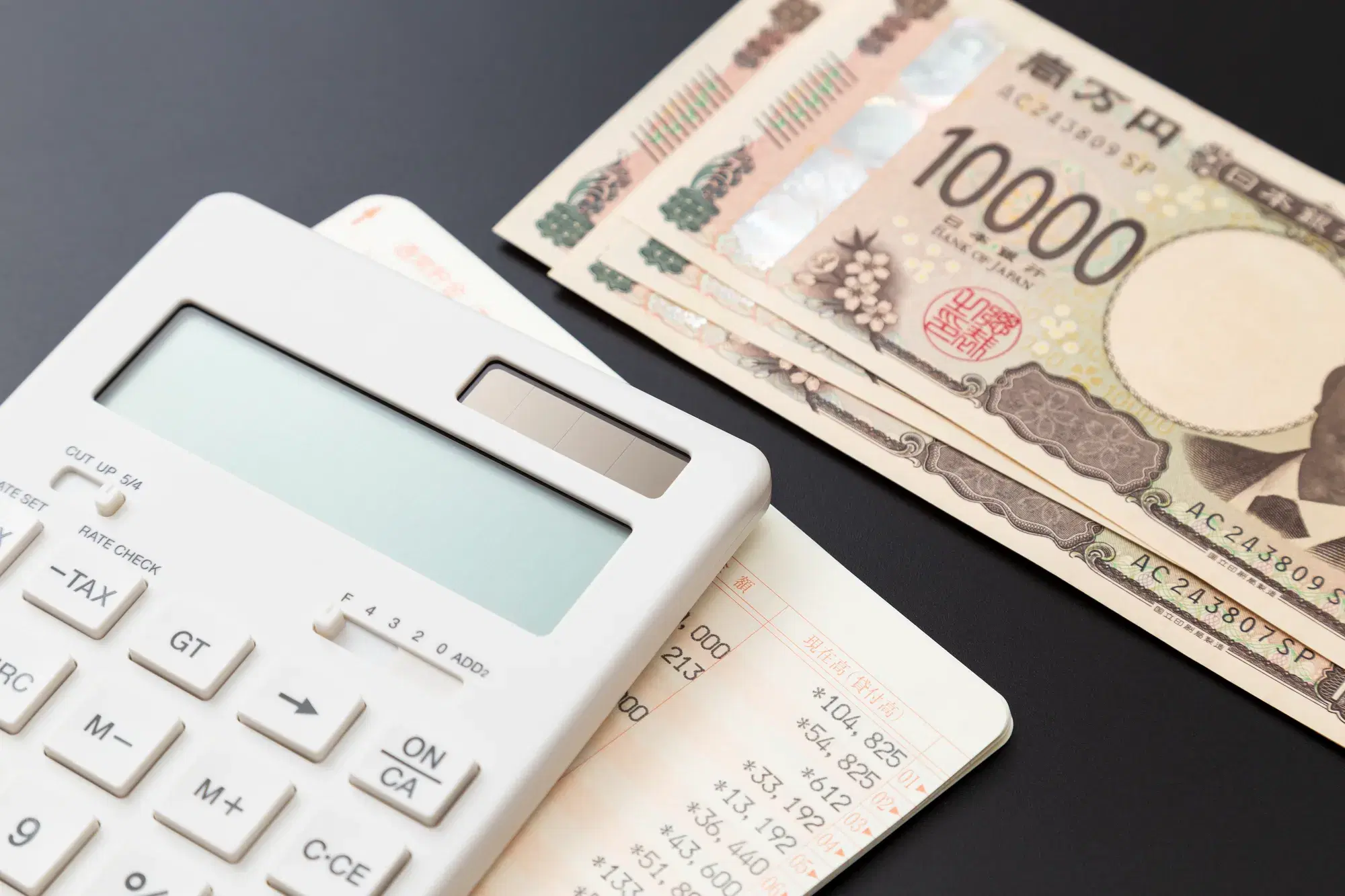 電卓と通帳と複数の一万円