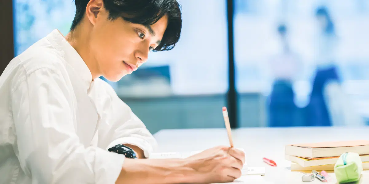 机に向かい勉強している男性