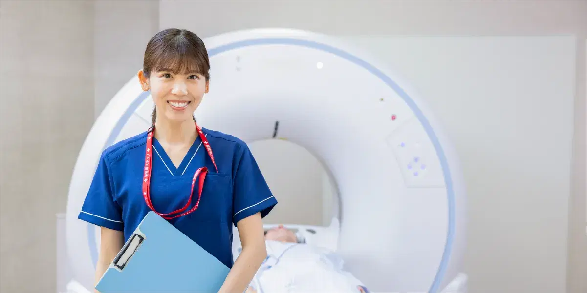 CTスキャナーの前に立つバインダーを持った女性技師