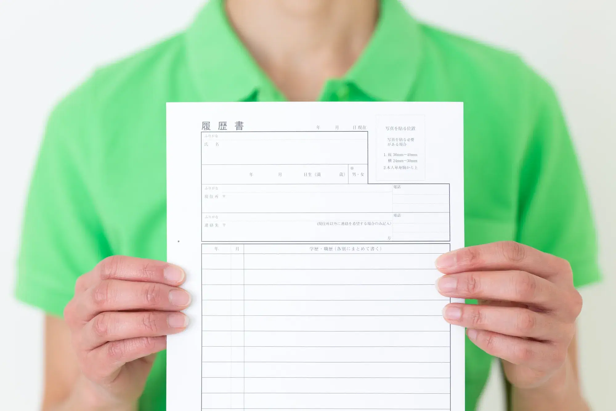 緑色の服を着た人が履歴書を見せている。