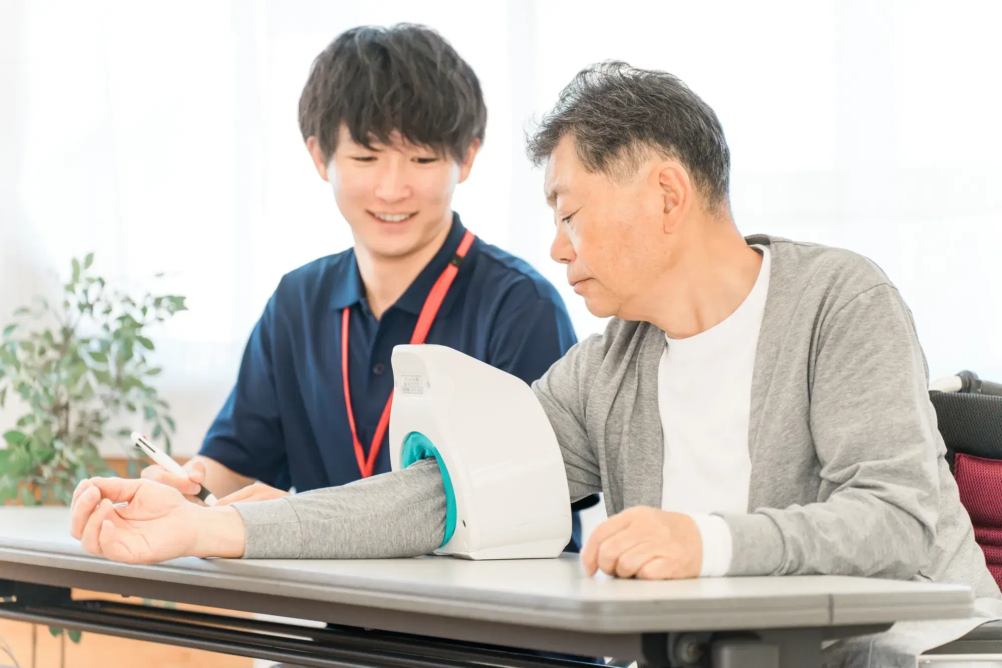 黒い服を着た男性が灰色の服を着た男性の血圧測定を介助