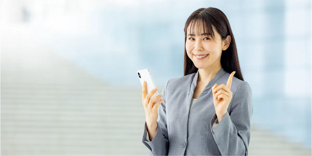 白いスマホを持ち指を立てている女性