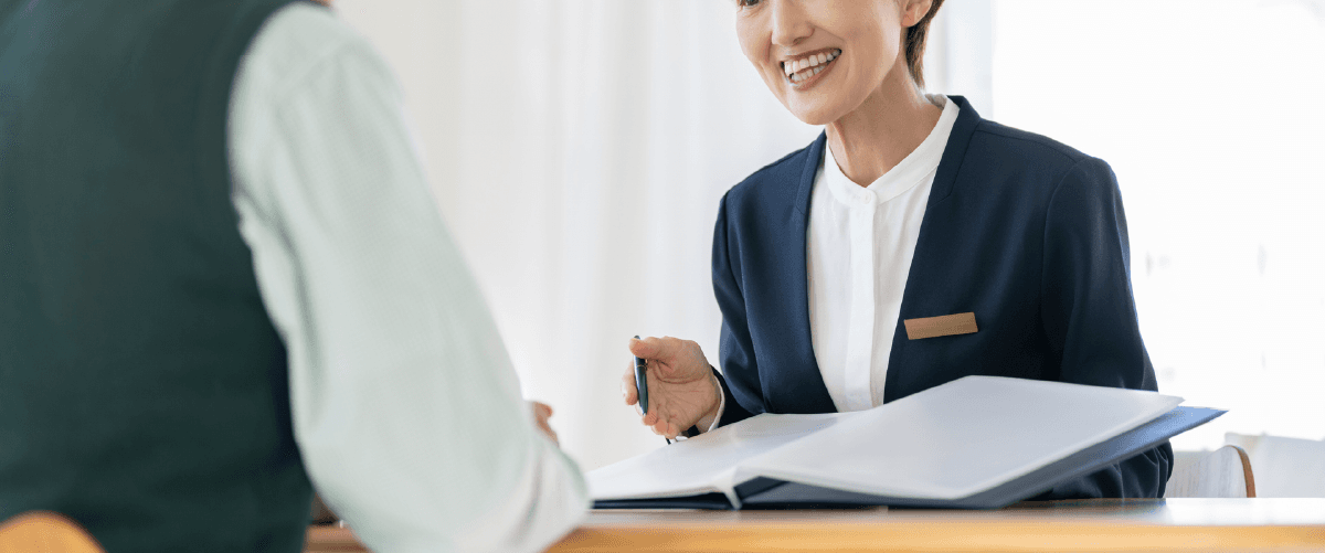 書類を見せながら話すスーツの女性