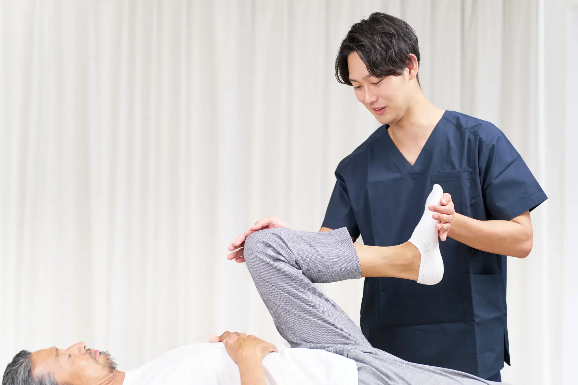 青い服を着た男性が年配の男性の足のケア