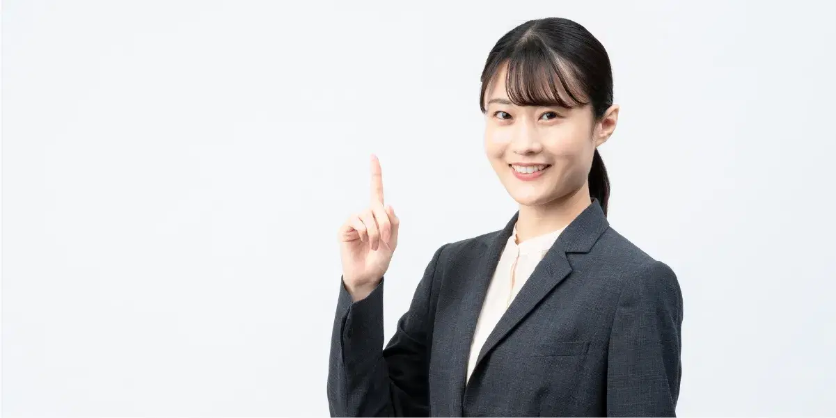 人差し指を立てるスーツの女性