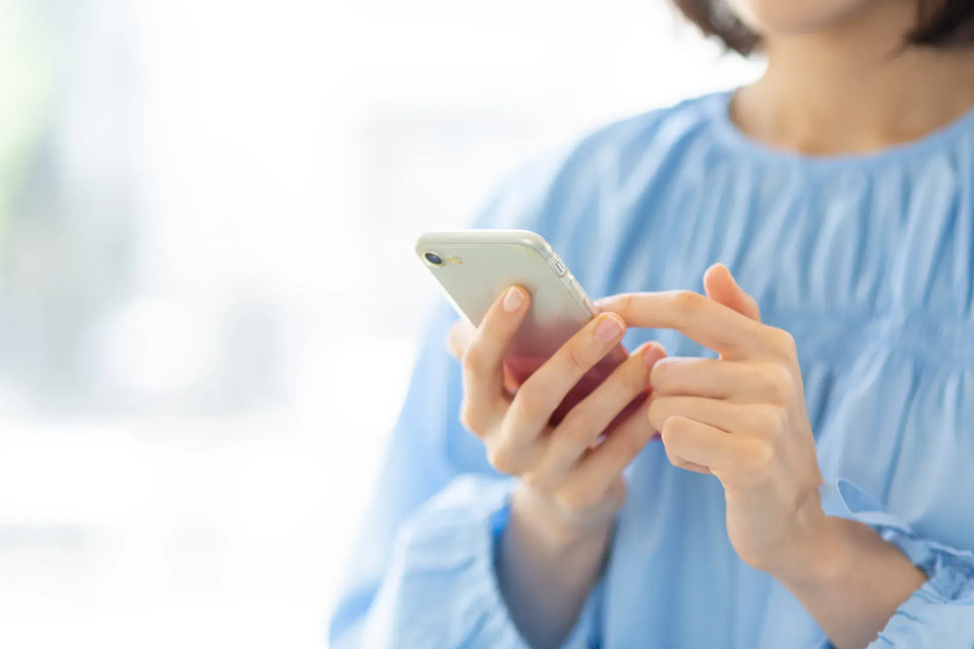 水色の服を着た女性がスマホを操作