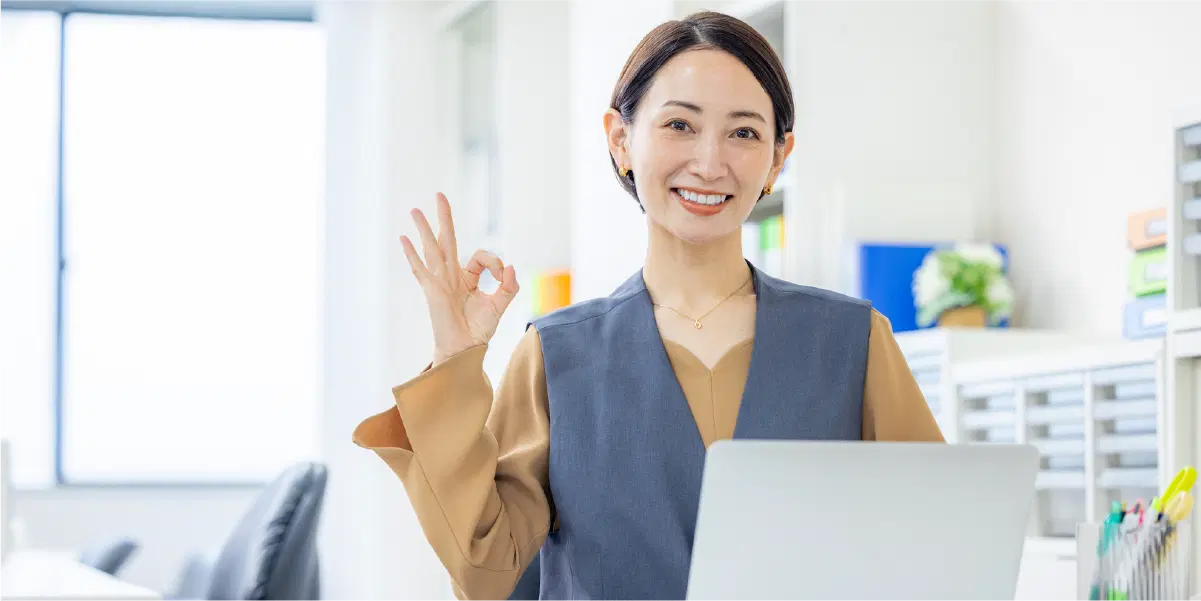 紙を持ち手で丸を作っている笑顔の女性