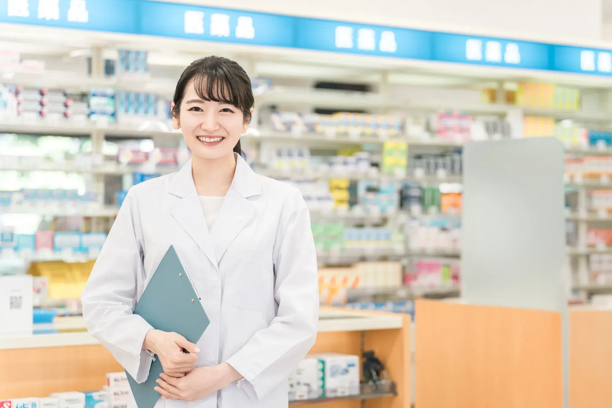 薬の陳列棚の前に薬剤師が立っている
