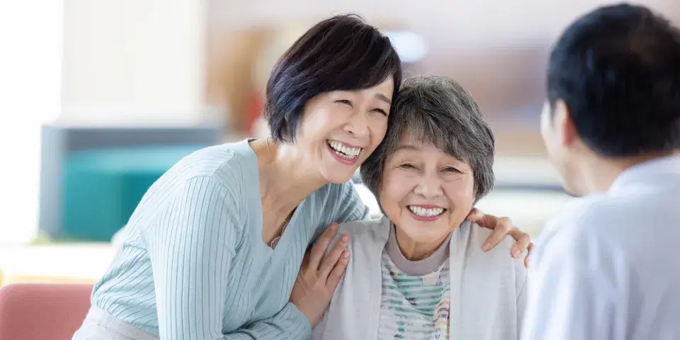 笑顔で高齢女性の肩を抱く女性